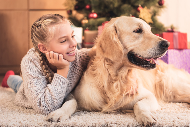 smiling youngster and funny dog lying near christmas tree at home - Fotografie, Obrázek