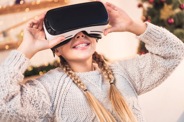 smiling female youngster using vr headset at christmastime - Foto, afbeelding