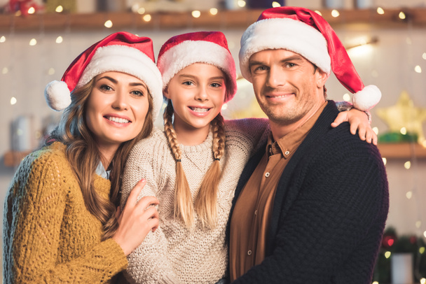 smiling family in santa hats hugging at christmastime - Fotó, kép