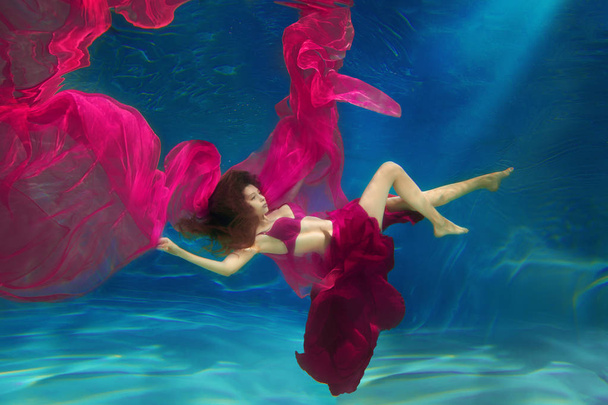 Girl mermaid. Underwater scene. A woman, a fashion model in the water in a beautiful dress swims like a fish - Photo, image
