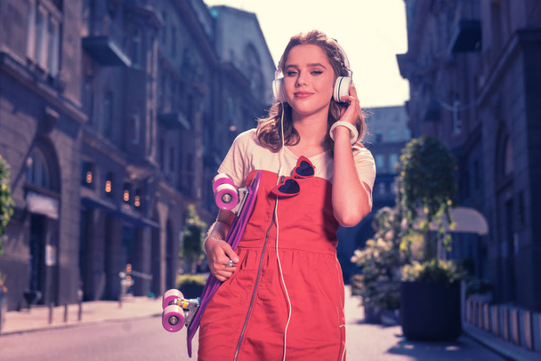 Beautiful student feeling relaxed while walking the street listening to music - Zdjęcie, obraz