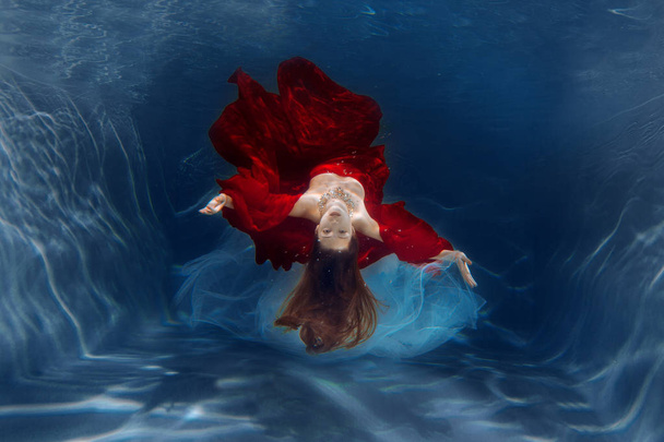 Girl mermaid. Underwater scene. A woman, a fashion model in the water in a beautiful dress swims like a fish - Zdjęcie, obraz