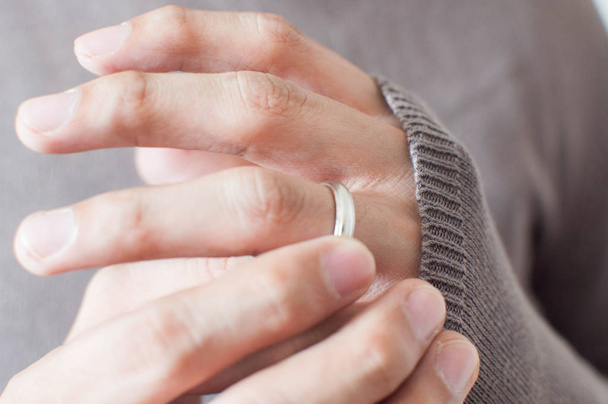 Κοντινό πλάνο των χεριών ενός ανθρώπου που φοράει ένα ασημένιο δαχτυλίδι - Φωτογραφία, εικόνα