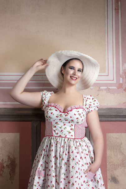 Pohled ženy mladá dáma krajinu s bílými šaty a červené květy a klobouk na opuštěný palác s staré nástěnné malby. - Fotografie, Obrázek