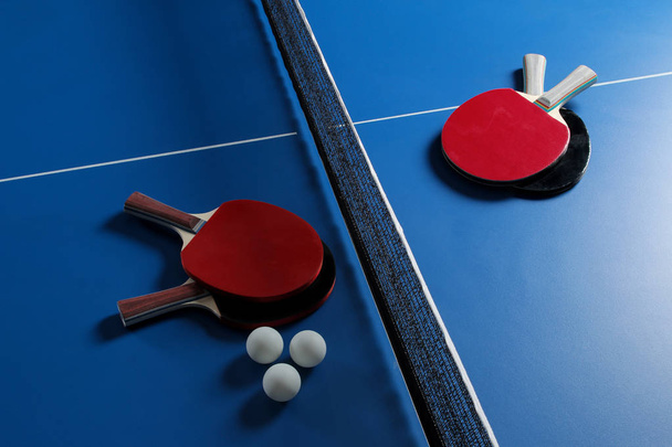 Ping pong. Accesorios para raqueta de tenis de mesa y pelota sobre una mesa de tenis azul. Deporte. Deporte juego
. - Foto, Imagen