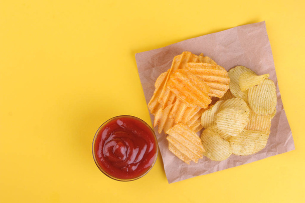 Diferentes tipos de papas fritas con salsa roja sobre un fondo amarillo brillante. vista desde arriba
 - Foto, imagen