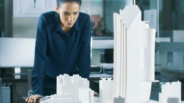 Female Architectural Designer Works on a Model of a City District with Buildings, Parks and It's Own Ecosystem. She Smiles. Beautiful Woman in Clean Minimalistic Office, Concrete Walls Covered by Blueprints and Documents. - Footage, Video