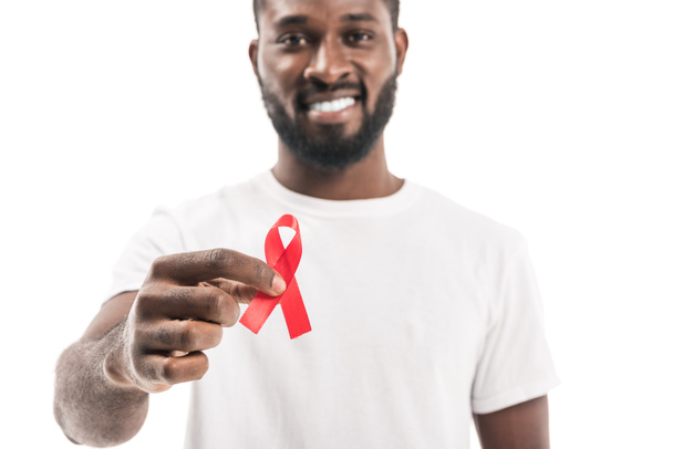 close-up shot of african american man in blank white t-shirt with aids awareness red ribbon looking at camera isolated on white - Foto, Imagen