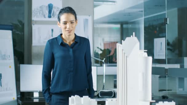 Female Architectural Designer Works on a Model of a City District with Buildings, Parks and It's Own Ecosystem. She Smiles. Beautiful Woman in Bright Minimalistic Office. - Filmagem, Vídeo