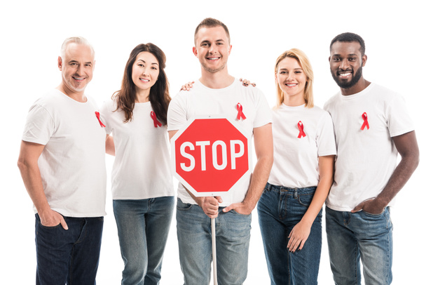 Grupa ludzi w puste białe t-shirty z aids świadomości czerwonymi wstążkami i znaku drogowego stop patrząc na kamery na białym tle - Zdjęcie, obraz