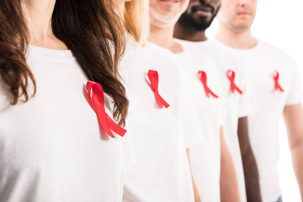 cropped shot of group of people in blank white t-shirts standing in row with aids awareness red ribbons isolated on white - Foto, afbeelding