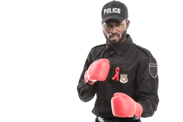 grimacing african american police officer with boxing gloves isolated on white, fighting aids concept - Photo, Image