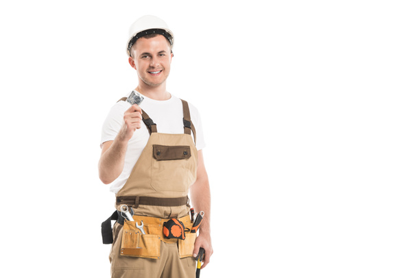 handsome adult builder holding condom and looking at camera isolated on white - Zdjęcie, obraz