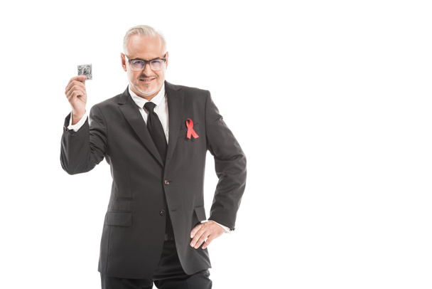 mature businessman in suit with aids awareness red ribbon isolated on white - Fotó, kép