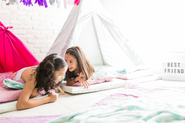 Preteen menina compartilhar segredos com amigo enquanto deitado na tenda tipi em casa
 - Foto, Imagem