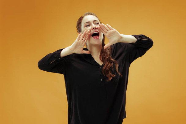 Isolated on orange young casual woman shouting at studio - Foto, imagen