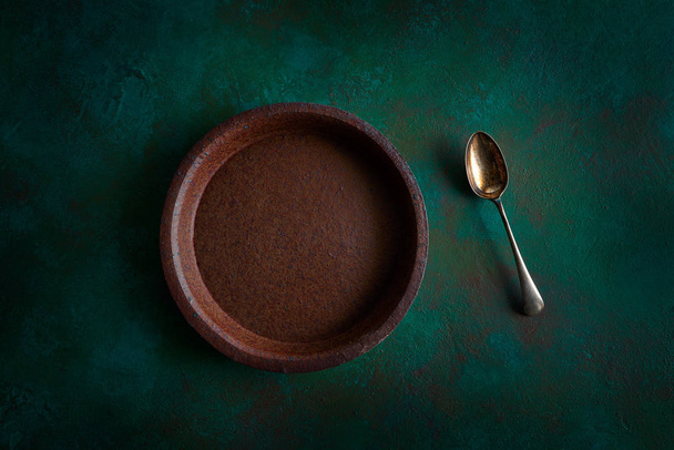 Ceramic tableware pottery plate on grunge green background and spoon - Photo, Image