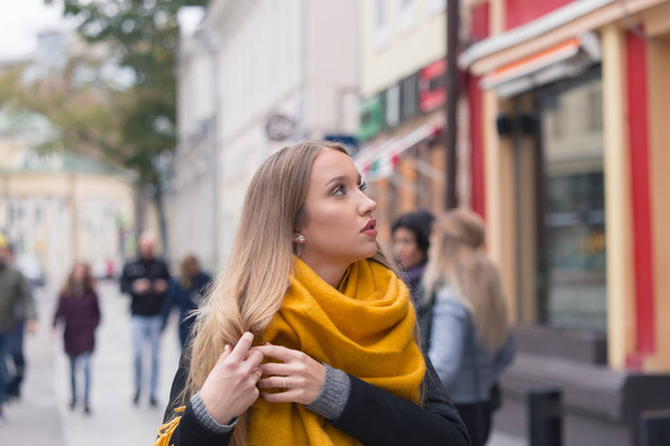 German tourist girl in the historical center of old Moscow. A blond woman with long hair in a coat and a yellow scarf. - Photo, Image