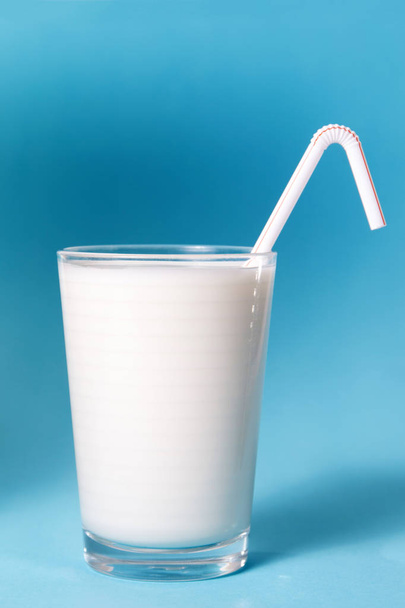 полный стакан молока с соломой на голубом фоне
. - Фото, изображение