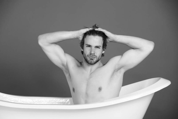 man with muscular body sitting in white bathtub - Foto, Imagem