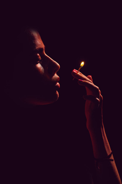 face of girl looking at burning match in hand - Valokuva, kuva