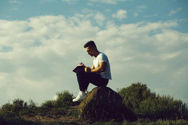 Pensive muscular man with book outdoor - Photo, Image