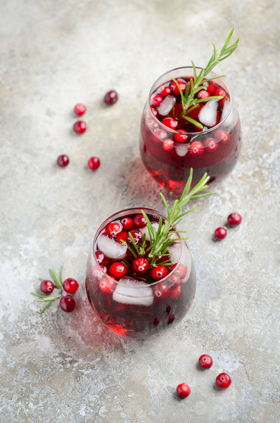 Cold refreshing drink with cranberries and rosemary on a gray concrete background - Фото, зображення