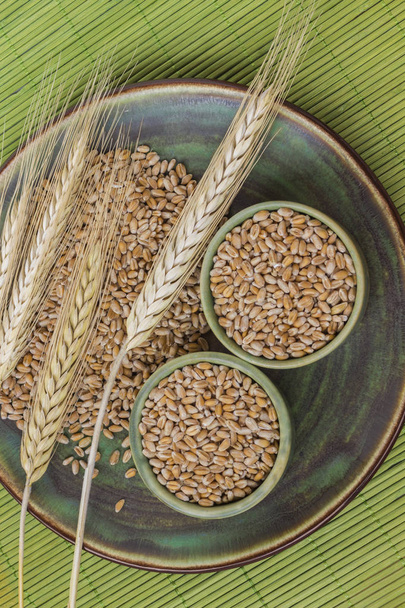 セラミック カップ、緑の背景に小麦の穂に小麦粒。トップ ビュー - 写真・画像