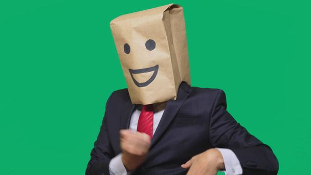 concept of emotions, gestures. a man with paper bags on his head, with a painted emoticon, smile, joy - Foto, afbeelding