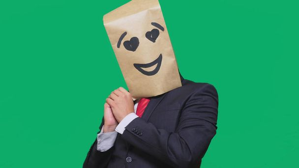 conceito de emoções, gestos. um homem com sacos de papel na cabeça, com um emoticon pintado, sorriso, alegria, olhos de amor
. - Foto, Imagem