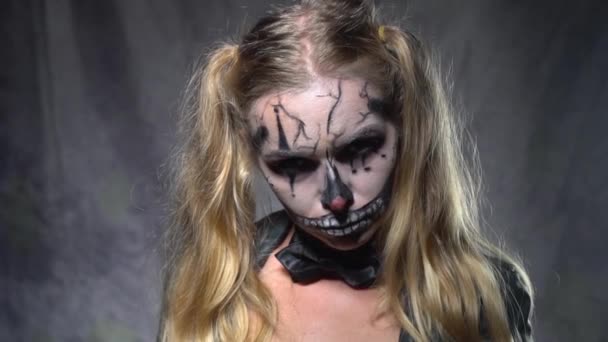 Closeup tvář ženy s strašidelný Halloween klaun lebka make-up pohledu a ukazoval zbraň do kamery. Kreativní, výtvarné, Halloween koncept - video v pomalém pohybu - Záběry, video