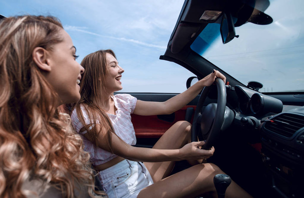 smiling girlfriends traveling in a convertible car. - Фото, зображення