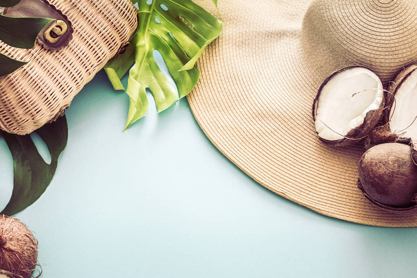 красочное лето с кокосами и пляжной шляпой на голубом фоне с настоящими тропическими листьями, летняя мода
 - Фото, изображение