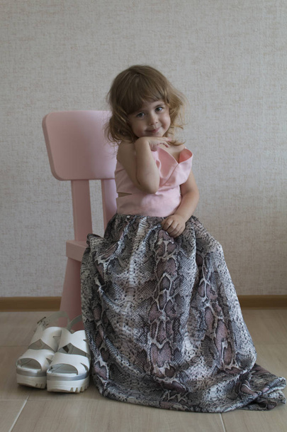 Trochu legrační dívka sedící v křesle v její matky velkým oblékat - Fotografie, Obrázek