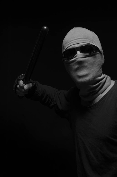 Ο άνθρωπος σε μια μάσκα με ένα μπαστούνι αστυνομίας. - Φωτογραφία, εικόνα