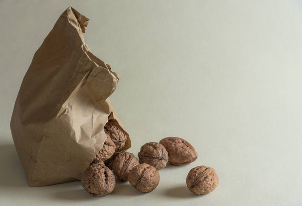 Walnuts overspill from a damaged paper bag on a green kitchen table - Photo, Image