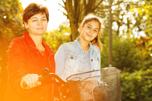Mother and daughter cycling in autumn park - Foto, imagen