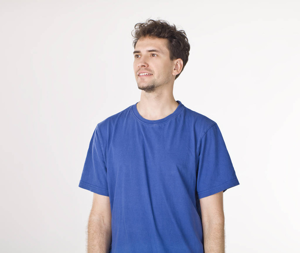 ausgeschnittenes Porträt eines jungen Mannes im blauen T-Shirt mit Blick nach rechts - Foto, Bild