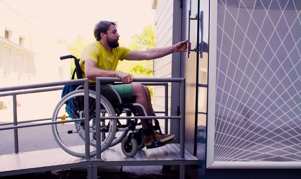 Jovem homem incapacitado em cadeira de rodas indo a uma WC público
 - Foto, Imagem