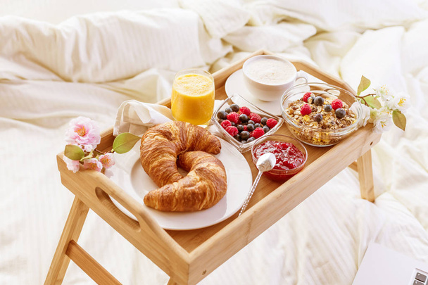 breakfast in bed with fruits and pastries on a tray - Foto, afbeelding