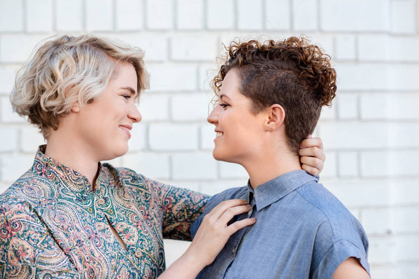 Affectionate young lesbian couple looking lovingly into each other's eyes while standing together on a city street outside - Photo, image