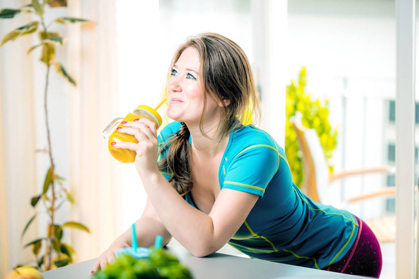 Фитнес молодая женщина пьет апельсиновый смузи
 - Фото, изображение