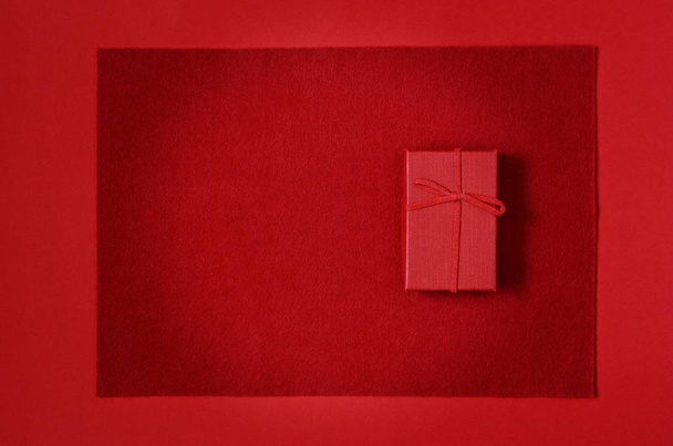 Red gift box on a red background. Romantic gift for Valentine's day.  Top view with place for text. - Φωτογραφία, εικόνα
