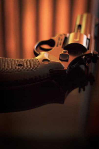 Pistola arma de pistola automática en la mesa en el dormitorio del hotel en la atmosférica foto dramática oscura
. - Foto, imagen