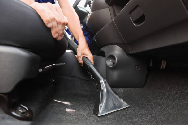 Man cleaning automobile salon with vacuum cleaner, closeup. Car wash service - Foto, afbeelding