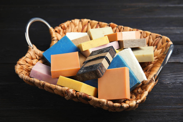 Many different handmade soap bars in wicker basket on table - Foto, Imagen