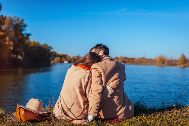 Młoda para w miłości chłodzenie przez jesień jezioro. Zadowolony mężczyzna i kobieta z przyrodą i przytulanie. Romantyczny daty - Zdjęcie, obraz