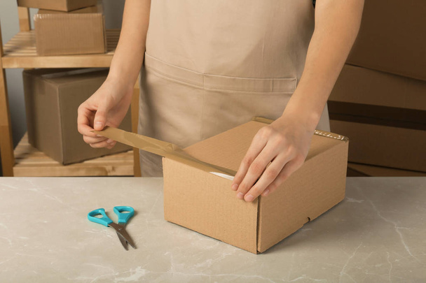 Woman packing box at table, closeup. Space for design - Foto, Bild