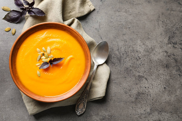 Flat lay composition with bowl of pumpkin soup and space for text on gray background - 写真・画像