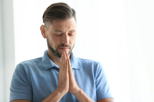 Man with hands clasped together for prayer on light background. Space for text - Foto, Imagem